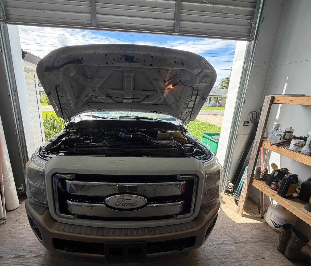 A Ford pickup with the hood up inside a shop building being serviced on site